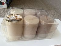 Front view of sealed six-pack showing two rows of pillar candles and product labels