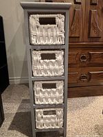 Front view of grey wooden shelf with four white woven basket drawers in place