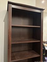 Frontal view upper portion showing dark brown wood finish and top moulding