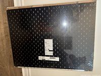 Front view of sealed black Ikea Skådis pegboard in plastic wrap