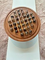 top view of wooden solitaire board filled with resin insect marbles