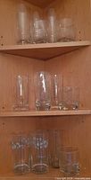 Corner cabinet shelves with assorted tall tumblers and short rocks glasses