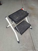 Stool unfolded showing both black plastic steps and white frame