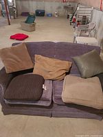 Overall view of five pillows on couch with storage bin visible in background