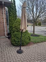 Closed beige patio umbrella on weighted base
