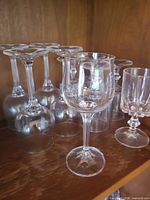 Front view of assorted wine glasses on shelf, one upright showing bowl and stem, others inverted