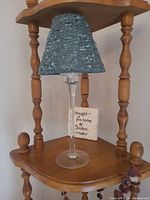Lamp with woven shade and wooden plaque on shelf