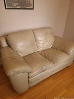 Front view of beige leather loveseat showing overall design and cushions