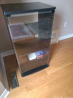 Front view of black media cabinet with glass door closed