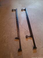Full view of both black metal side rails showing overall length and casters