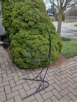 full view of black metal plant stand with basket outdoors