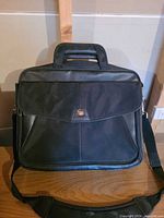 Front view of black nylon laptop bag with flap and shoulder strap