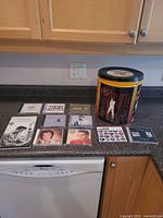 Group shot of ten CDs and collectible tin