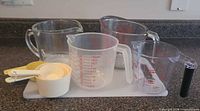 Four liquid measuring jugs, nested dry cups and cutting board overview