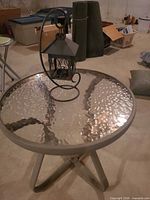 Side view of round glass patio table with lantern on top