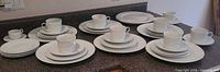 Complete dinnerware set laid out on countertop showing multiple place settings