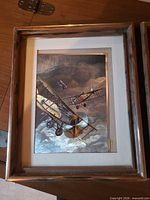 first framed print showing two biplanes in flight, matte and frame visible