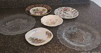 Six plates laid out showing variety of porcelain and glass pieces
