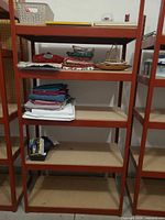 Front view of red metal shelving unit with contents present for scale