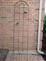 Full view of arched metal trellis leaning against brick wall