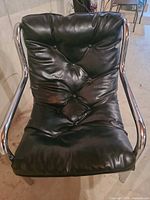 Front view showing black tufted leather seat and chrome arms