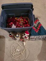 Overview of tote with ornaments, tree skirt, figurines, plush toy and light cord