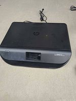 HP Envy inkjet printer top and front view with attached power cord