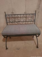 Front view of wrought iron bench with gray cushion