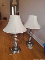 Both matching brushed nickel table lamps with cords coiled on floor