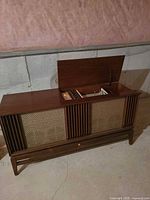 Full view of closed console showing wood cabinet, speaker fronts, overall condition