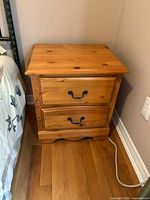 Front view of pine nightstand beside bed