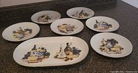 All seven round plates and oval platter arranged on countertop