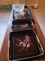 Overview of three decorative trays stacked and clear cut glass bowl