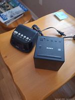 Sony cube clock radio and Westclox clock radio on table, cords visible