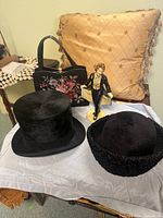 Group view showing top hat, ladies hat, figurine and handbag