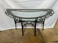 Front view of glass demilune table showing scrollwork base