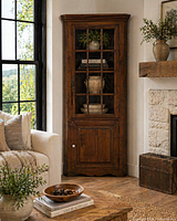 Staged view of rustic solid wood corner cabinet in a living room setting