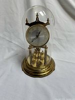 Full view of Kundo torsion clock under glass dome on brass base
