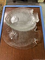 Two clear glass fish platters on surface