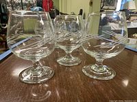 Three etched glass brandy snifters on table displaying shape and pattern