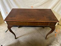 Full front view of dark brown solid wood console table showing rectangular top and four cabriole legs