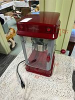 Front angled view of red Sunbeam kettle popcorn maker showing crank arm and size annotations