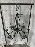 Full view of chandelier hanging on temporary stand showing eight arms, chain, and canopy