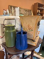 Green enamel milk canister, blue enamel watering pitcher and cream painted planter displayed together