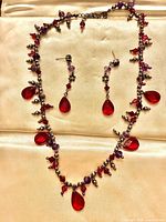Full view of necklace and earrings laid on cream fabric