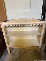 Front view of unfinished pine bookcase with two shelves and floral frieze