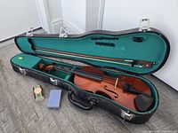 Violin in open hard case with bow, rosin, sponge visible