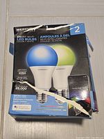 Front of damaged box showing two colour-change bulbs, specs 1050 lumen, 11 W, 25 000 h