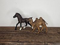 Camel and foal figurines side by side on wooden surface