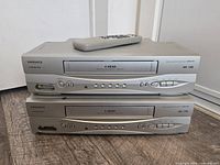 Two stacked Magnavox CMWV405 VCRs with remote on top